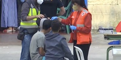 Una voluntaria atiende a varios menores no acompañados a su llegada a Ceuta el pasado mes de mayo.